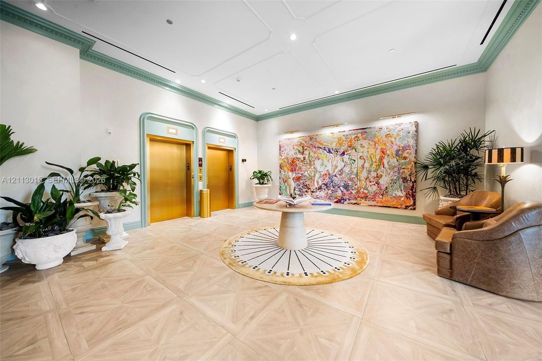 Elevator lobby featuring geometric wood-finish flooring, custom decorative molding, dual brass-finish elevator doors, and recessed ceiling lighting