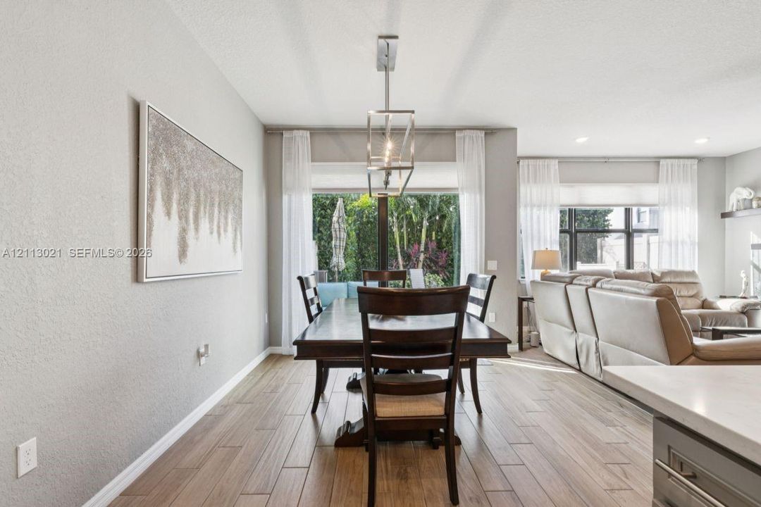 Wood-finish tile flooring, recessed lighting, and a geometric metal pendant fixture