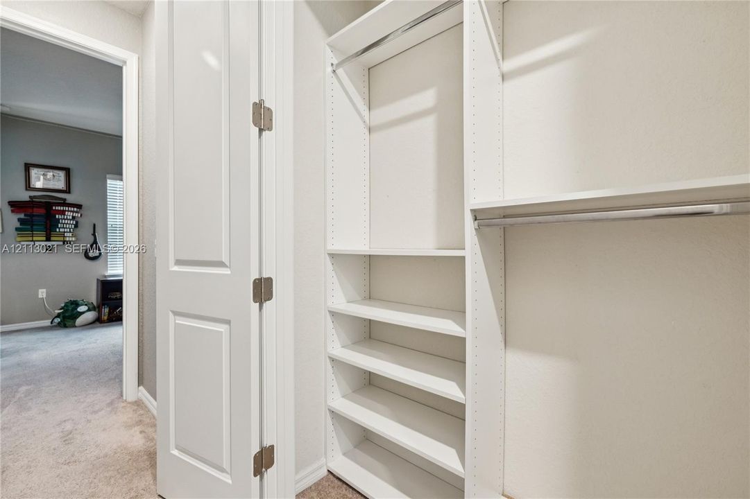 Custom built-in closet organization featuring adjustable shelving, integrated hanging rods, and a white finish