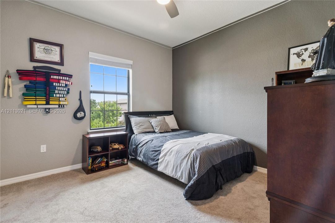 Bedroom featuring neutral wall paint, carpeted flooring, a single-hung window with a grid pattern, and a ceiling-mounted light fixture