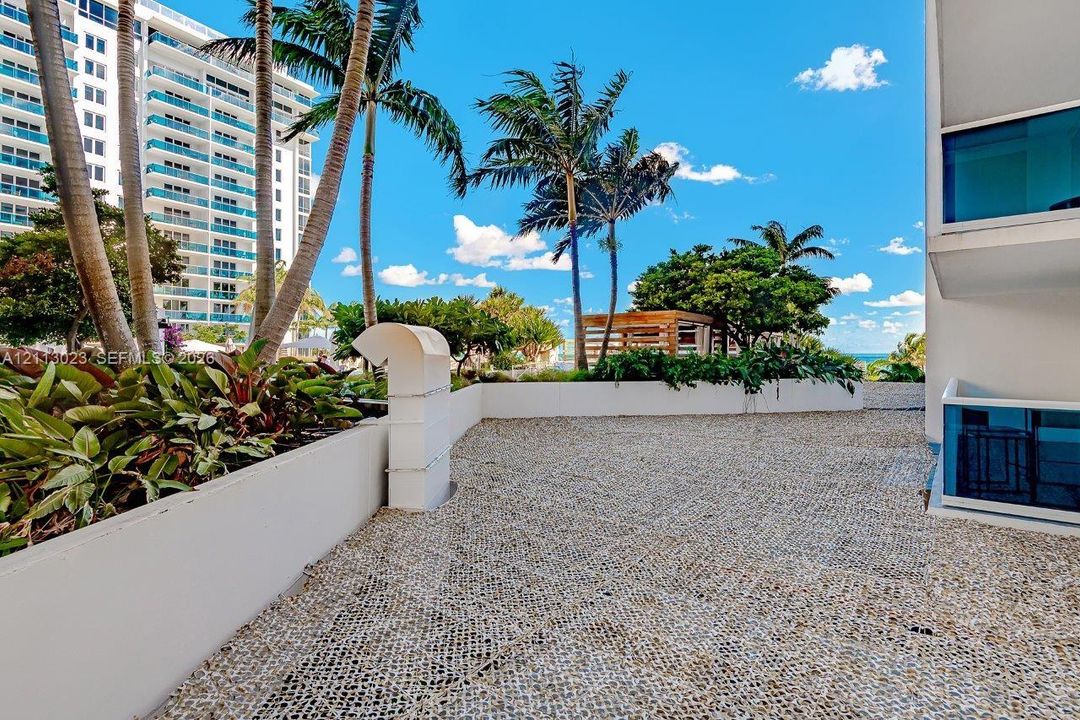 Outdoor terrace featuring patterned paver flooring, perimeter concrete planter walls, and palm tree landscaping