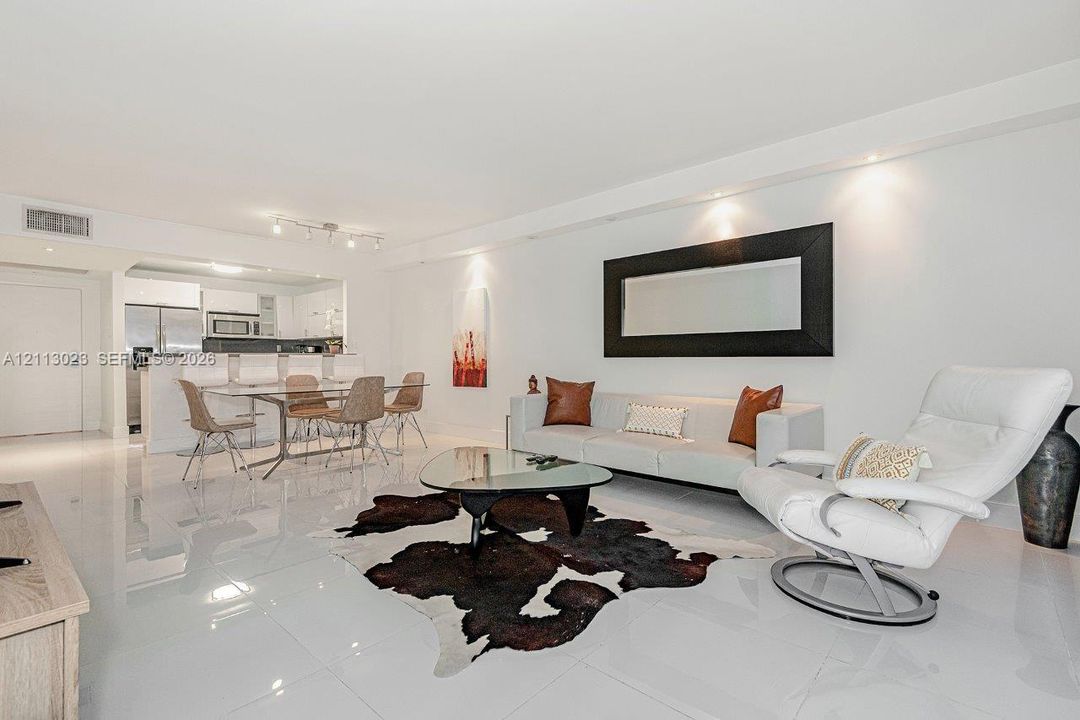 Open-concept living space featuring high-gloss tile flooring, recessed ceiling lighting, and a breakfast bar with stone-finish countertops