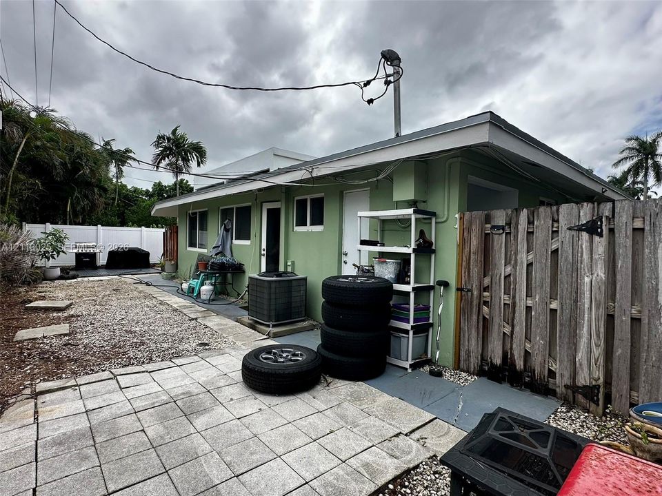 Exterior side yard featuring concrete paver patio, gravel ground cover, and a vertical wood privacy fence