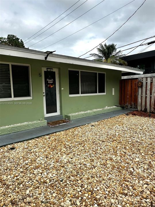 Exterior featuring a painted finish, low-slope roofline, concrete walkway, and gravel yard area