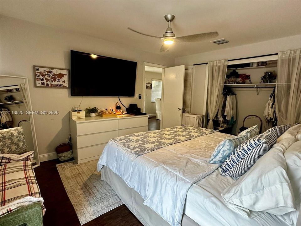 Bedroom featuring dark-toned flooring, a brushed nickel ceiling fan with integrated lighting, and a reach-in closet with built-in shelving