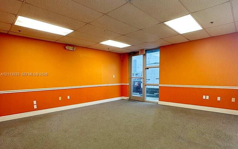 Interior space featuring high-contrast two-tone wall finishes, a drop ceiling with recessed rectangular lighting panels, and a glass-paneled entry door