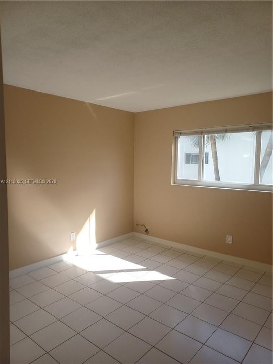 Neutral-toned interior featuring ceramic tile flooring and a horizontal sliding window