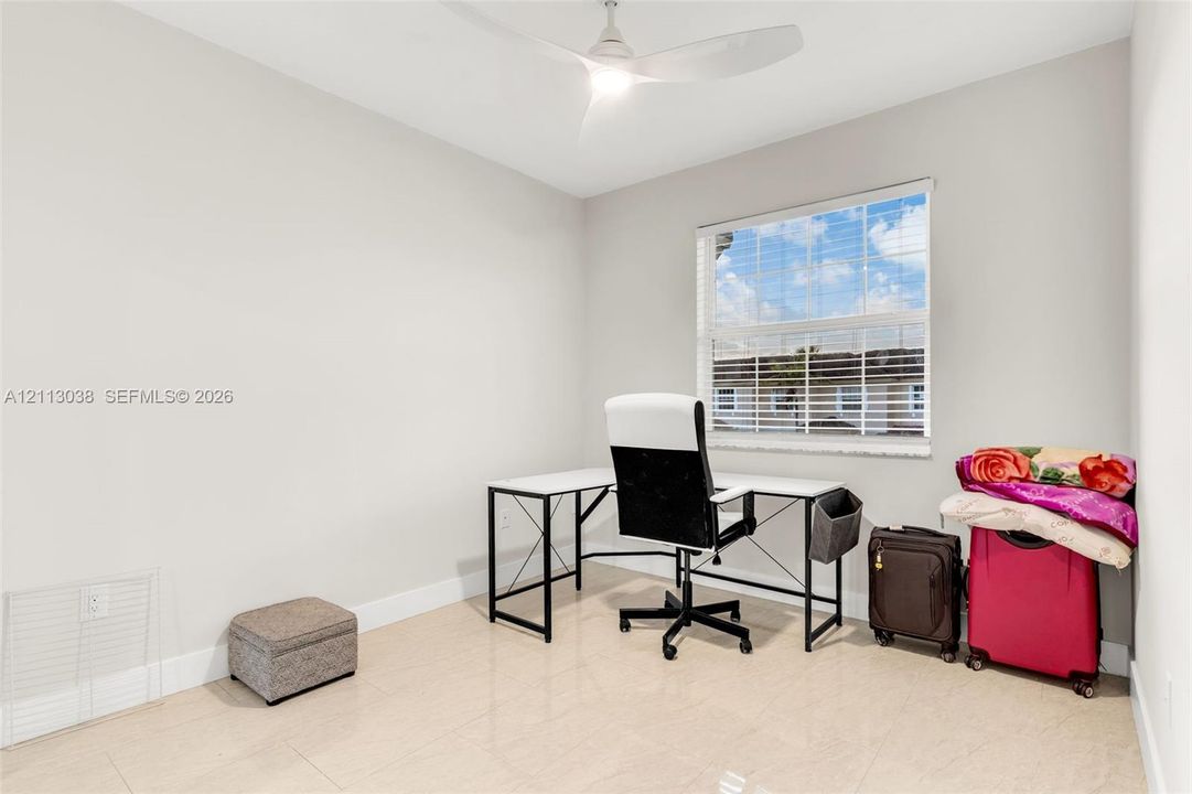 Neutral-toned room featuring tile flooring, a multi-blade ceiling fan with integrated lighting, and a window with horizontal blinds