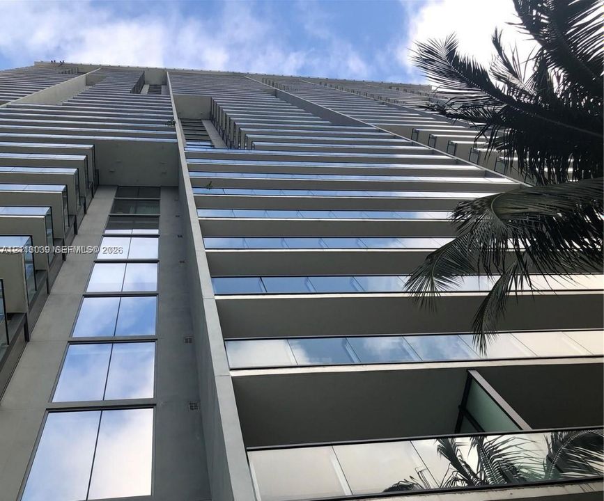 High-rise architectural exterior featuring glass-paneled balconies, concrete structural elements, and floor-to-ceiling windows