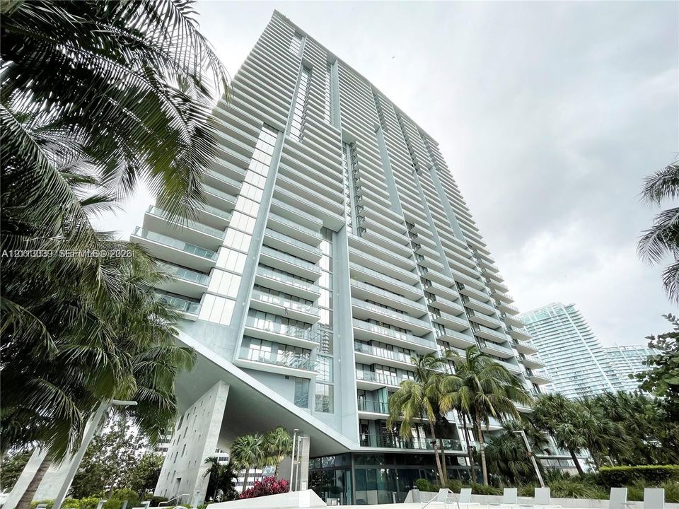 High-rise structure featuring floor-to-ceiling glass paneling, cantilevered architectural design, and private balconies with glass railings