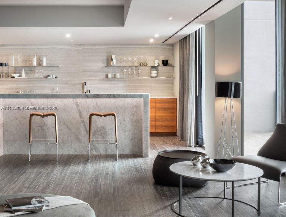 Stone-surfaced kitchen island with waterfall edge, wood-finish flooring, custom wood-tone cabinetry, and tiered glass shelving