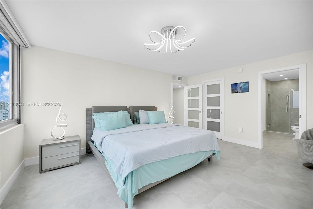 Neutral-toned tile flooring, contemporary multi-arm flush-mount lighting, large-format window, and dual white-framed doors with frosted glass inserts