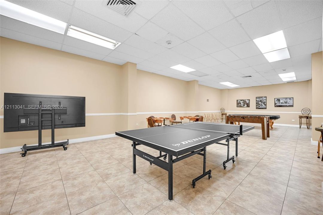Open-concept interior space featuring neutral wall paint, tile flooring, recessed drop-ceiling grid lighting, and chair rail molding