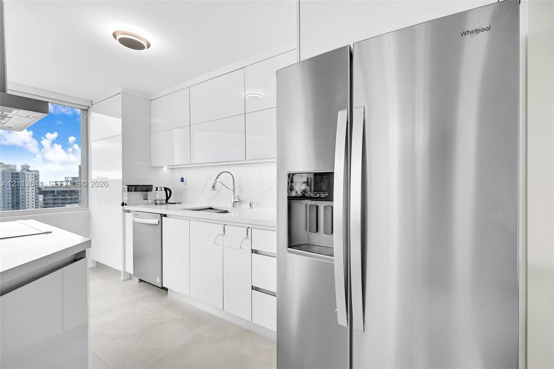 Kitchen featuring high-gloss white cabinetry, stone-surface countertops, stainless steel side-by-side refrigerator, stainless steel dishwasher, and large-format tile flooring
