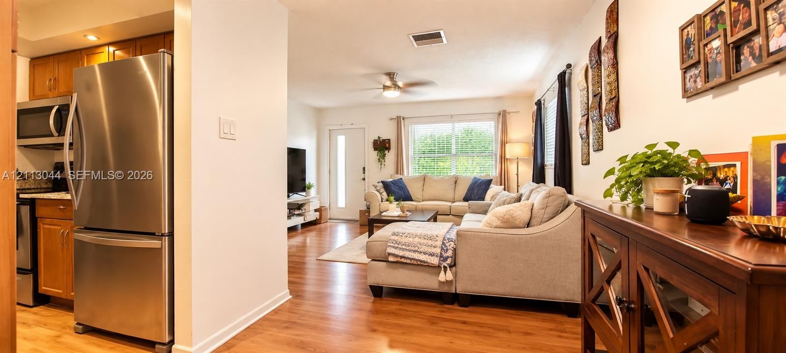 Kitchen featuring stainless steel refrigerator and microwave, wood-finish flooring, and ceiling fan