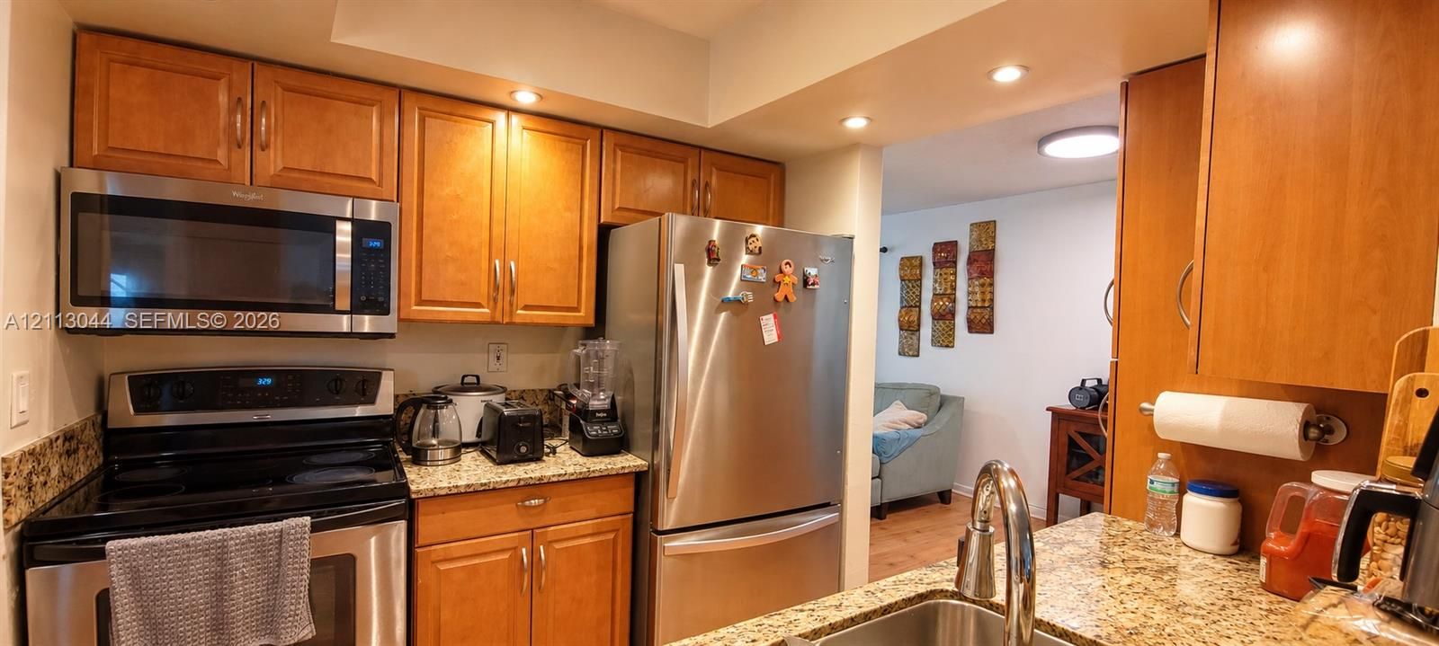 Kitchen featuring stone-finish countertops, stainless steel appliances, custom wood-finish cabinetry, and recessed lighting