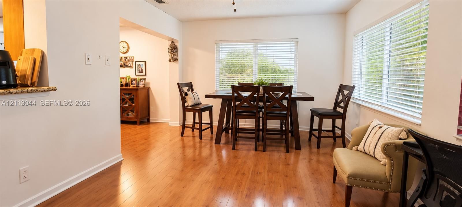 Open-concept dining area featuring wood-finish flooring, dual-aspect windows, and horizontal blinds