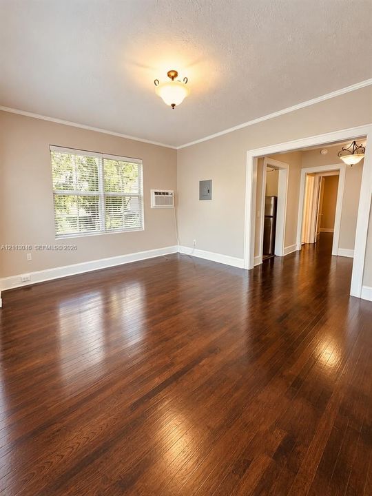 Wood-finish flooring, neutral wall tones, multi-pane window, and classic semi-flush mount ceiling lighting