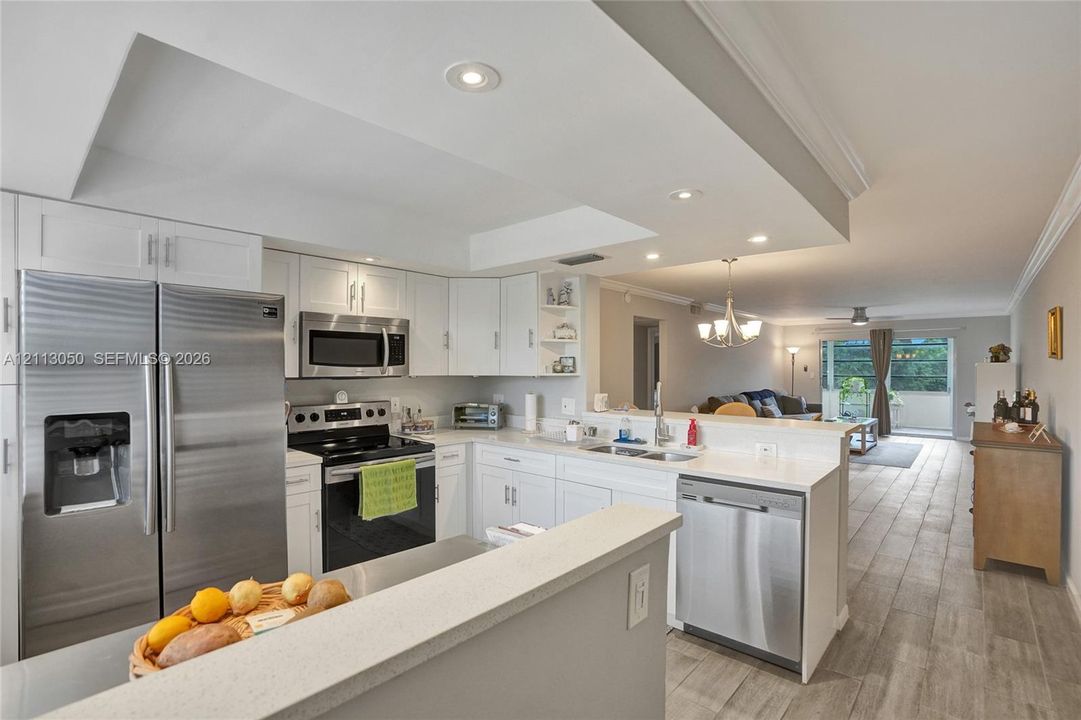 Kitchen featuring white shaker-style cabinetry, stainless steel appliances, recessed ceiling lighting, and wood-finish flooring throughout the main space