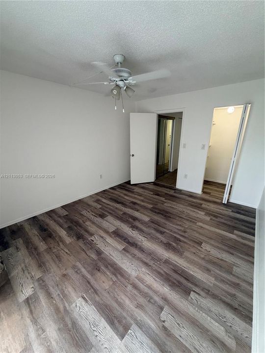 Wood-finish flooring, ceiling-mounted fan with integrated lighting, and dual doorway access to independent storage areas