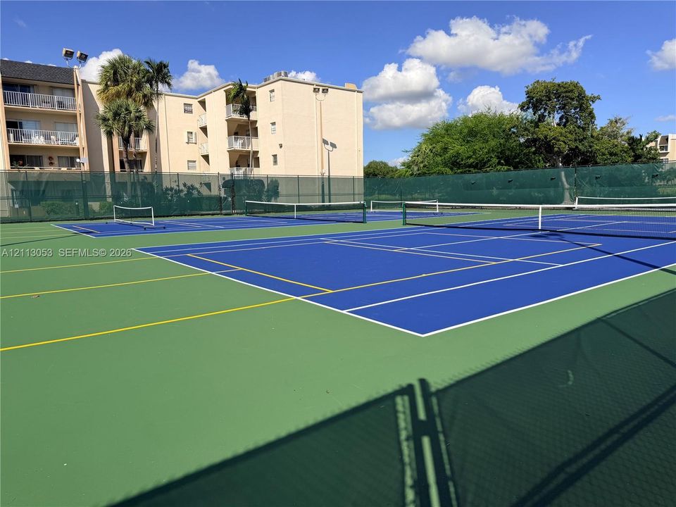 Multi-court facility featuring blue and green acrylic surfacing, perimeter chain-link fencing, and installed netting