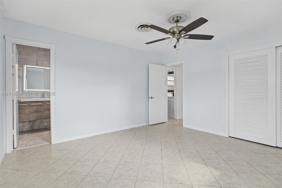 Room featuring tile flooring, ceiling fan with integrated lighting, and dual-door louvered closet