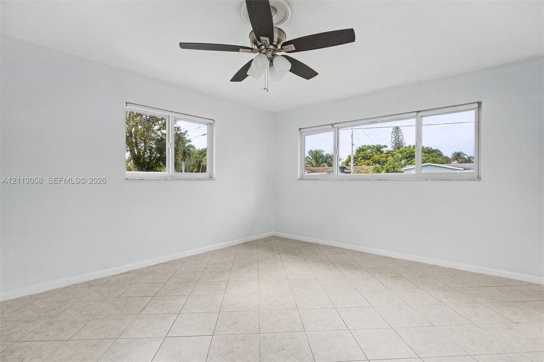 Neutral-toned tile flooring, multi-pane windows, and a ceiling fan with integrated lighting