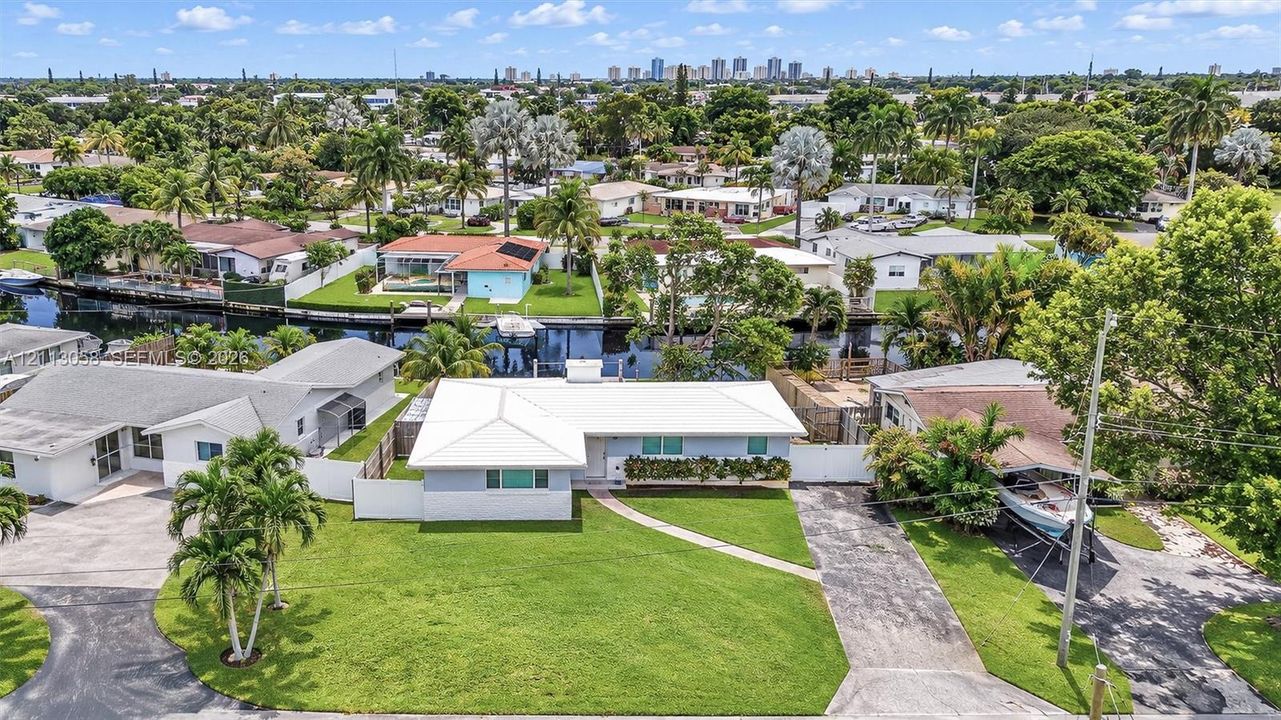 Single-story residence featuring a metal roof, attached asphalt driveway, manicured lawn, and water frontage with a bulkhead
