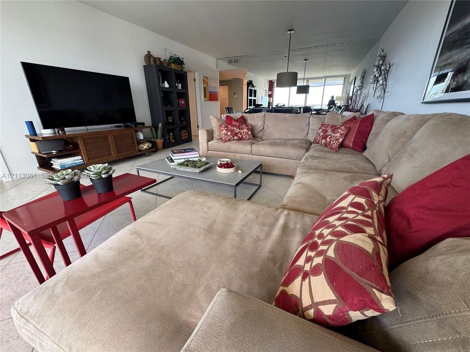 Living area featuring large-format tile flooring, floor-to-ceiling mirrored wall, and floor-to-ceiling windows