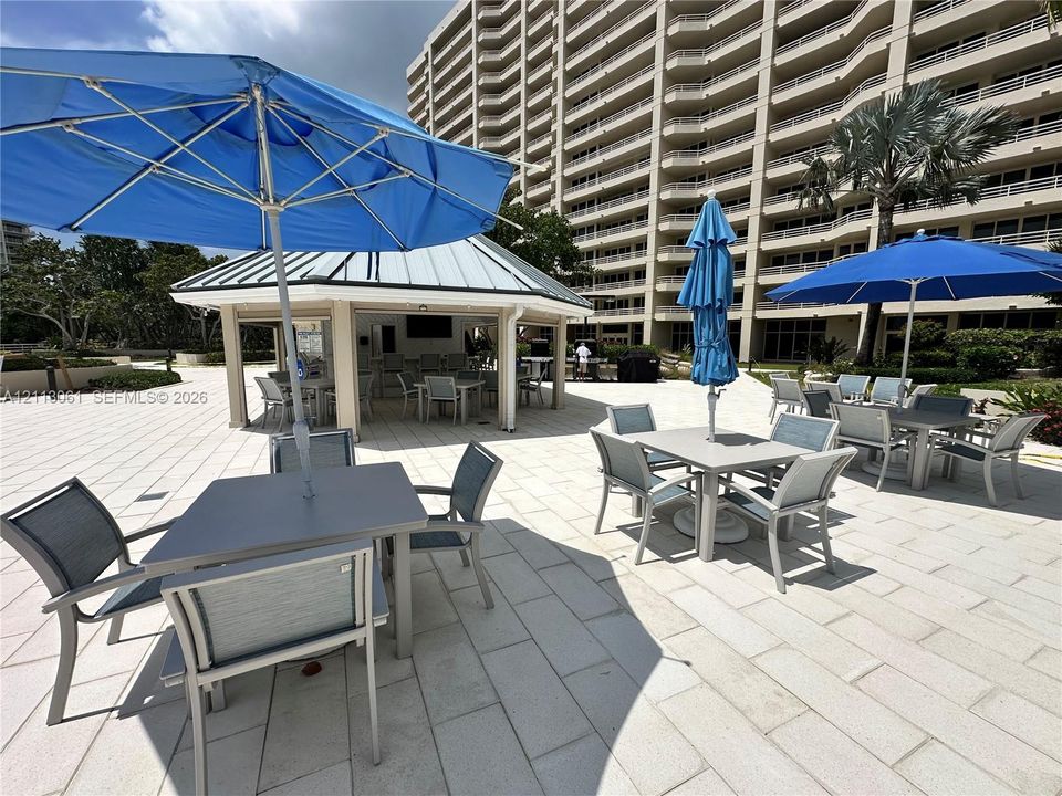 Expansive stone-paved patio featuring a covered pavilion with a metal roof and recessed lighting