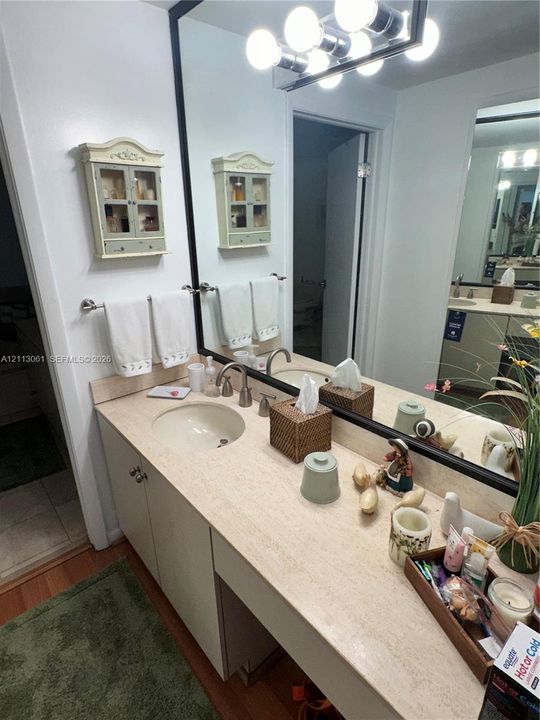Bathroom vanity featuring a solid-surface countertop, an integrated oval sink, a brushed metal faucet, a full-width mirror with a black frame, and a multi-bulb light fixture