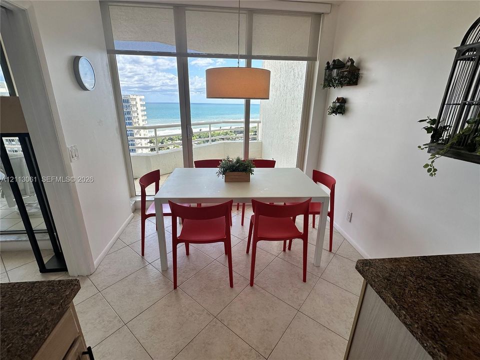 Floor-to-ceiling windows featuring ocean scenery, tile flooring, and a drum pendant light fixture