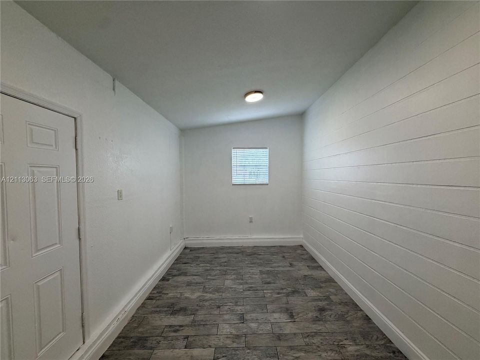 Interior space featuring wood-finish tile flooring, horizontal shiplap wall paneling, a recessed ceiling light, and a single window