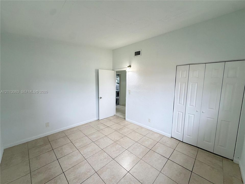 Neutral-toned square tile flooring, four-panel closet doors, and smooth-finish walls