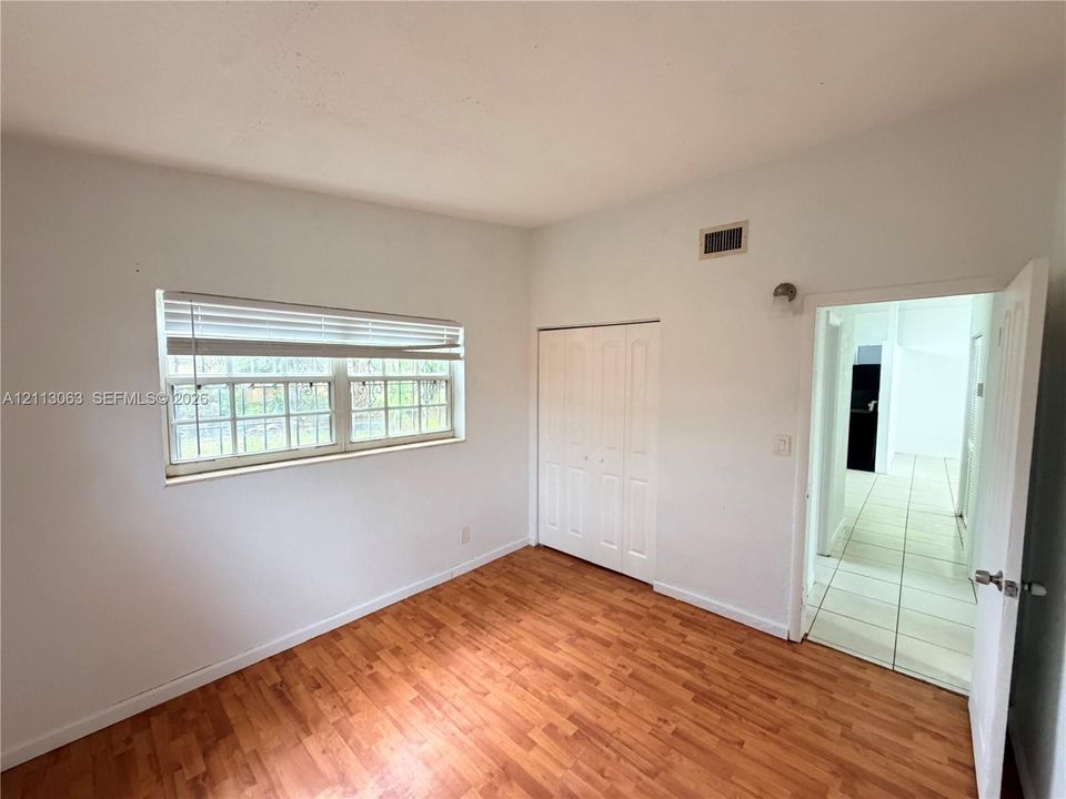 Room with wood-finish flooring, multi-pane window, and built-in closet featuring double-panel doors