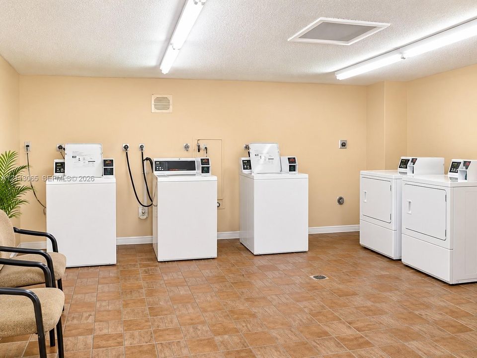 Laundry facility featuring multiple washer and dryer units, tile flooring, and overhead strip lighting