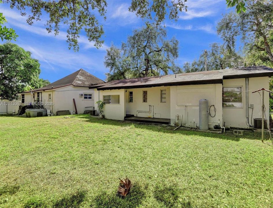 Expansive backyard featuring a sprawling lawn, mature trees, and dual detached structures with exterior siding