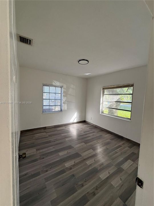 Interior room featuring wood-finish flooring, two windows with horizontal panes, and a flush-mount circular ceiling light