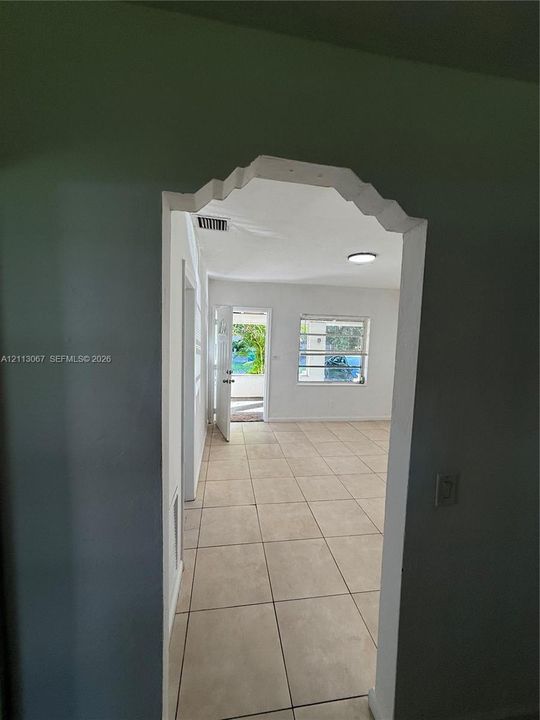 Decorative arched doorway featuring intricate molding, large-format tile flooring, and flush-mount ceiling lighting