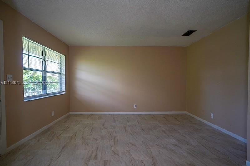 Interior space featuring neutral-toned walls, textured ceiling, stone-finish tile flooring, and a single-pane horizontal window