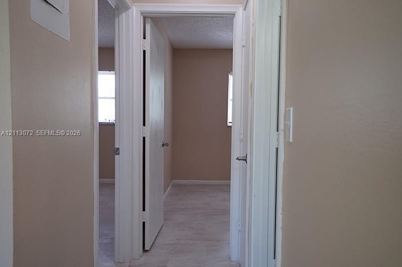 Interior corridor with neutral wall paint, white door casings, white multi-panel interior doors, and tile flooring
