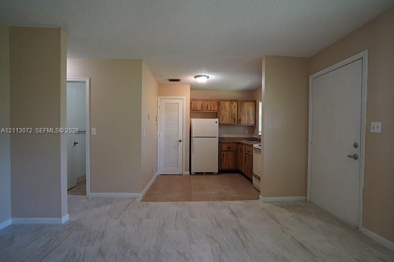 Kitchen featuring wood cabinetry, tile flooring, and a louvered-door pantry