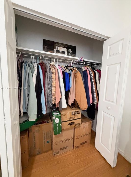 Reach-in closet featuring white six-panel bi-fold doors, a wire shelving system, and wood-finish flooring
