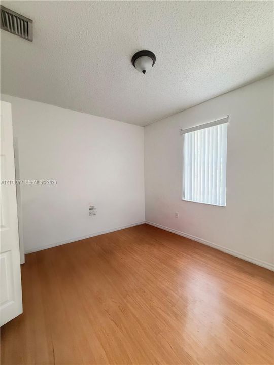 Interior room featuring wood-finish flooring, a single-pane window with vertical blinds, and a semi-flush mount dome ceiling light