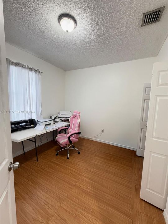 Interior room featuring wood-finish flooring, a flush-mount ceiling light fixture, and a single-panel interior door