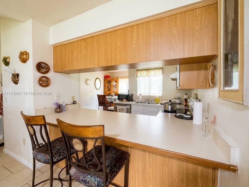 Kitchen featuring wood-finish cabinetry, an extended breakfast bar with a solid surface countertop, and tile flooring