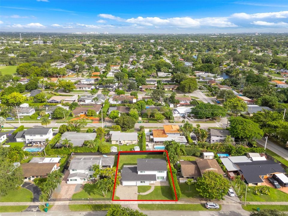 Two-story residence featuring a shingle roof, attached garage, paved driveway, and expansive lawn with perimeter landscaping