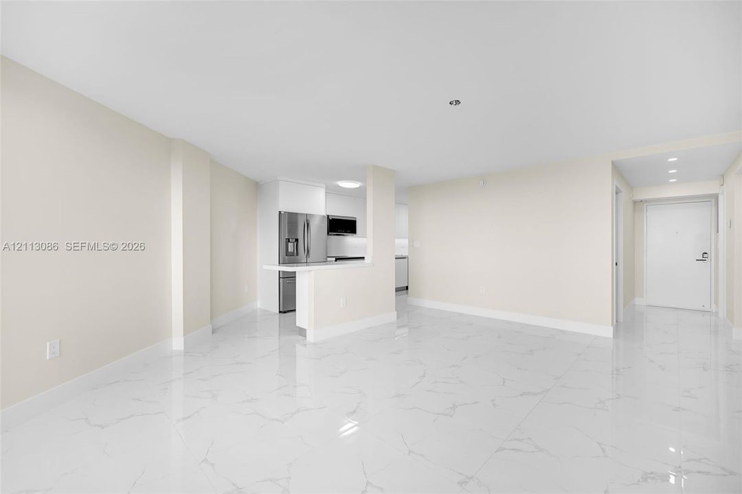 Open-concept interior featuring large-format tile flooring with a veined pattern, a breakfast bar with a solid surface countertop, stainless steel kitchen appliances, and recessed ceiling lighting