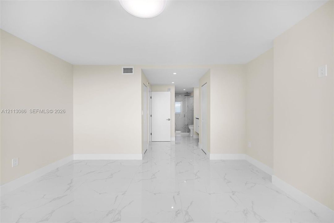 Bright interior space featuring polished white tile flooring with grey veining, crisp neutral walls, and recessed lighting
