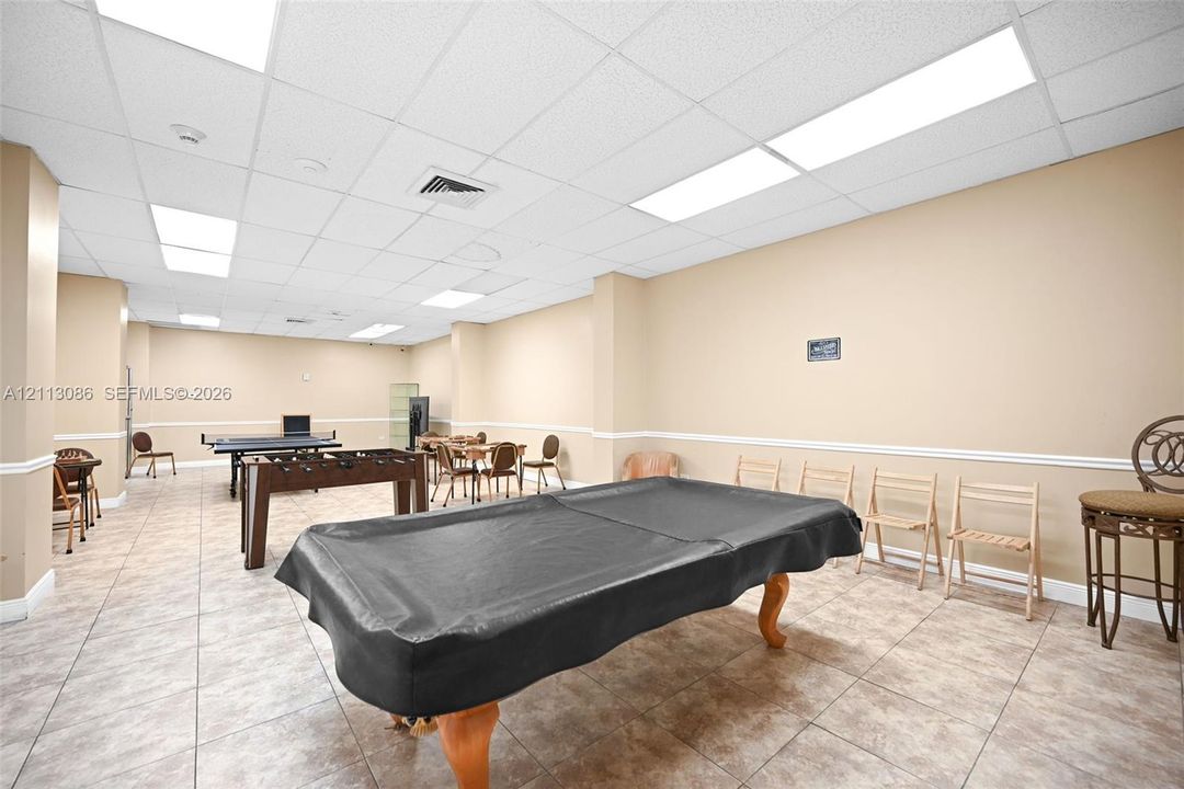 Large multipurpose room featuring neutral wall paint, tile flooring, recessed drop-ceiling panels, and integrated linear lighting